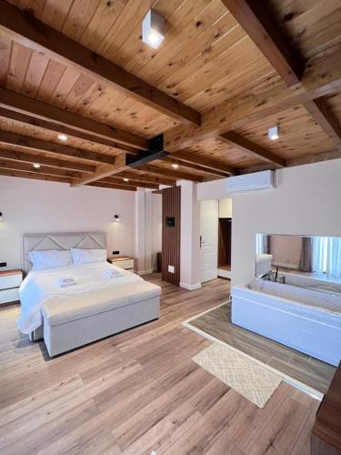 a bedroom with a white bed and a wooden ceiling at Hotel Vila Ami in Tragjas