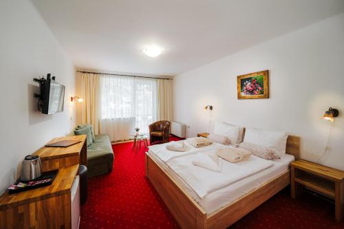 a hotel room with a large bed and a couch at Hotel Elenka in Veľký Meder