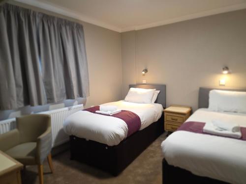 a hotel room with two beds and a chair at The Paddington House in Warrington