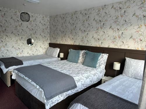two beds in a hotel room with floral wallpaper at The Cross Keys in Worthington