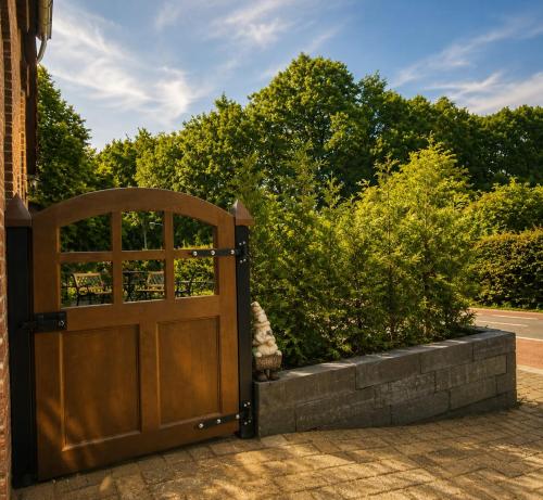 an open wooden door in front of some bushes at 'tNest Middelaar in Middelaar