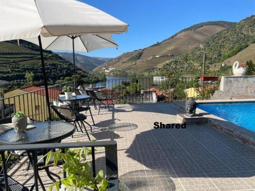 a patio with tables and an umbrella and a pool at Casa Nunes in Pinhão