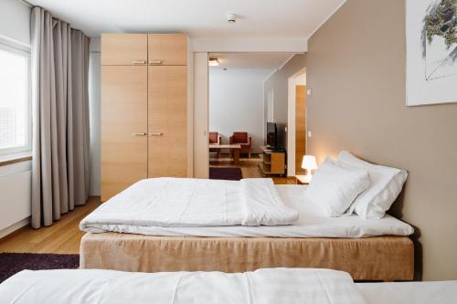 a bedroom with two beds and a living room at Hotel Rantapuisto in Helsinki