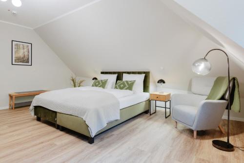 a white bedroom with a bed and a chair at HarzHold - Apartmenthotel in Osterode