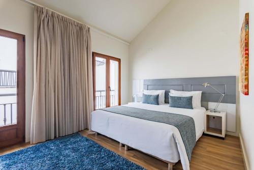 a bedroom with a large bed with a blue rug at Porta da Arrábida Suites in Palmela