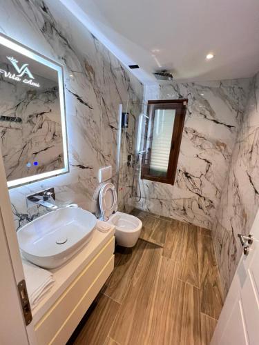 a bathroom with a white sink and a toilet at Hotel Vila Ami in Tragjas