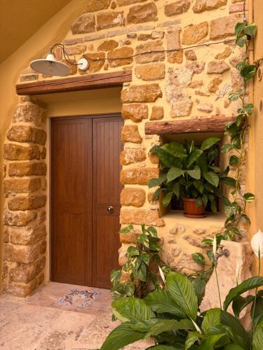 a stone building with a wooden door and a plant at BeB Omare Agrigento in Agrigento