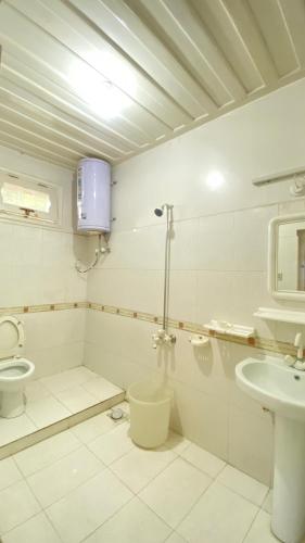 a white bathroom with a toilet and a sink at Comfort Inn in Chitral