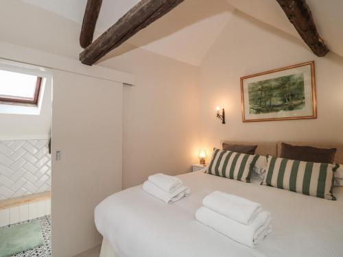 a bedroom with a white bed with towels on it at Wheelwright Cottage in Moreton in Marsh
