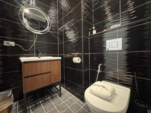 a black tiled bathroom with a toilet and a sink at 安平胡桃民宿-免費停車-專屬電梯-公園景觀 #包棟可使用娛樂設施 in Tainan