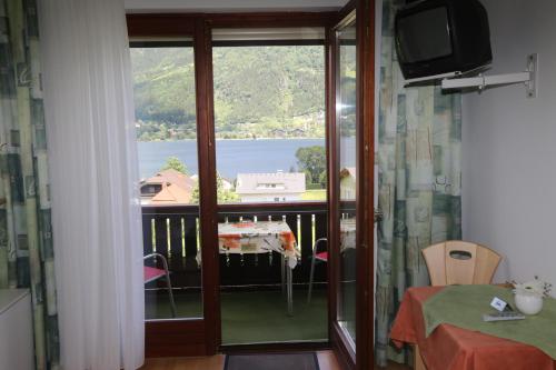 a room with a balcony with a view of the water at Gästehaus Luise in Ossiach