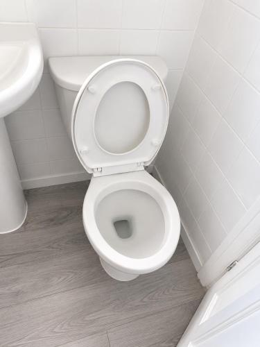 a white bathroom with a toilet and a sink at 2BR Mariners Stay - Newhaven in Newhaven