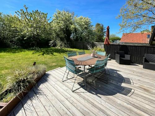 a wooden deck with a table and chairs and an umbrella at Summer House With Authentic Charm On Enø in Karrebæksminde