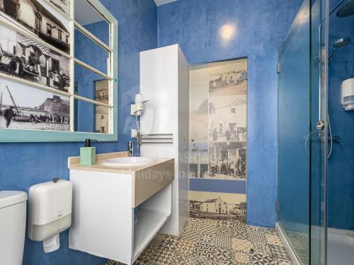 a blue bathroom with a sink and a shower at Casas da villa - Apartments in Ericeira
