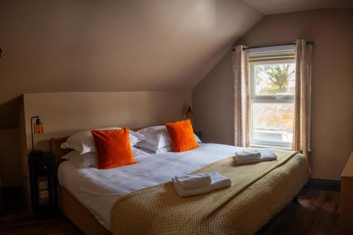 a bedroom with a bed with orange pillows and a window at Tommy Jacks Beach Apartments in Bude