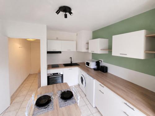 a kitchen with white cabinets and a wooden table at Studio avec terrasse et jardin privatif - Figeac centre - Parking gratuit in Figeac