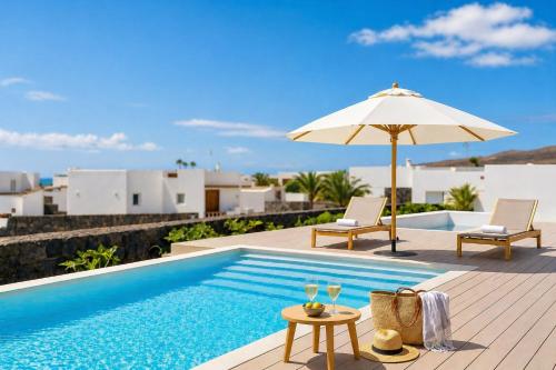 a pool with an umbrella and chairs and a table at Villa Ainé Luxury Villa, Sea Views, Heated pool in Puerto Calero