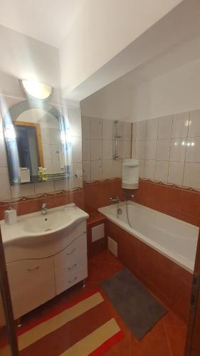 a bathroom with two sinks and a tub and a mirror at Apartament RHC in Târgu Ocna