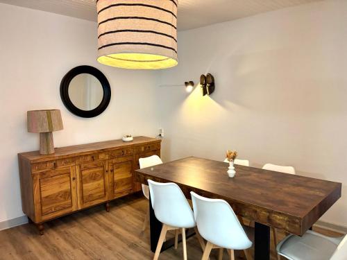 a dining room with a wooden table and white chairs at Chez le Sabotier, central et confortable in Rosières