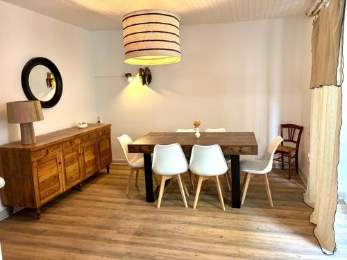 a dining room with a wooden table and white chairs at Chez le Sabotier, central et confortable in Rosières
