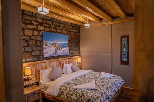 a bedroom with a bed and a stone wall at Shan at Uley in Leh