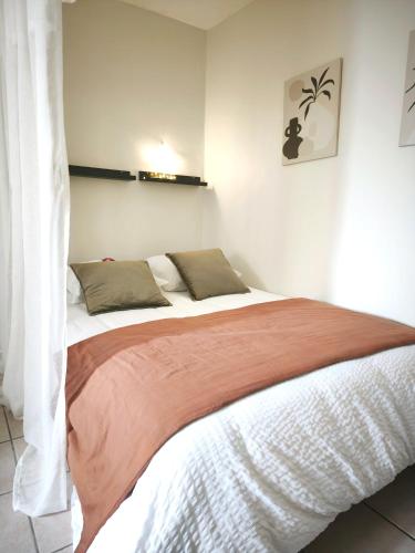 a bedroom with a large bed with a orange blanket at La Petite Escale in Lunel