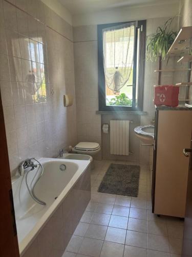a bathroom with a tub and a toilet and a window at Como Gate - 10 minuti dal centro in Lucino
