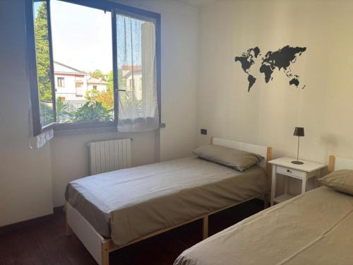 two beds in a room with a world map on the wall at Como Gate - 10 minuti dal centro in Lucino