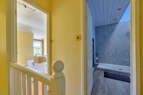 a hallway with yellow walls and a staircase with a window at Finest Retreats - Delfryn in Talysarn