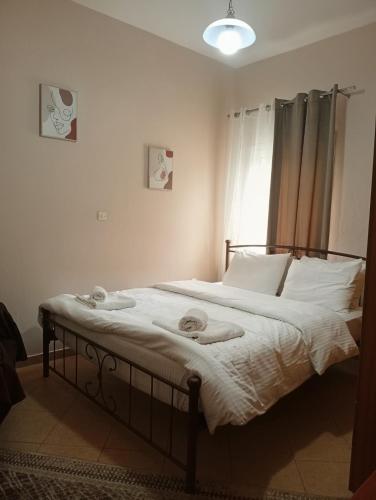 a bedroom with a bed with white sheets and a window at Gamila Sunrise in Konitsa