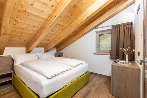 a bed in a room with a wooden ceiling at ChaletMafi in Valdidentro