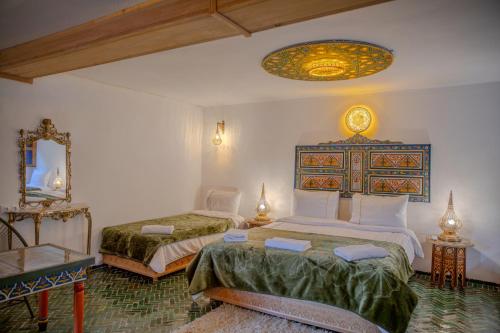 a bedroom with two beds and a mirror at Riad Old City Palace in Fez