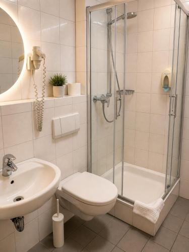 a bathroom with a shower and a toilet and a sink at Hotel Panorama Nickenich in Nickenich