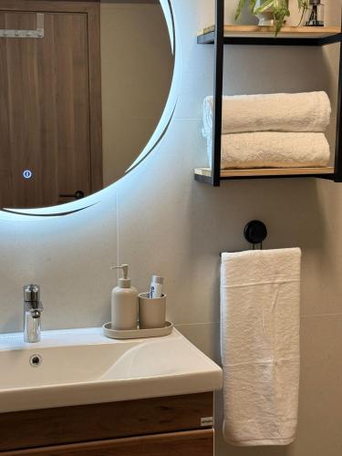 a bathroom with a sink with a mirror and towels at Apartman Andrea in Posušje