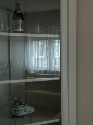 a glass shelf with a vase on a table at Central apartment 4 in Gnjilane