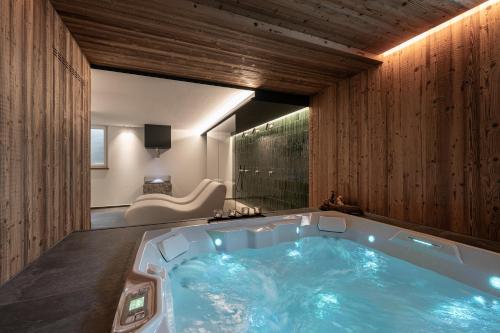 a jacuzzi tub in a room with wooden walls at Hotel alle Rose Family inspired garden and SPA in Cavedago