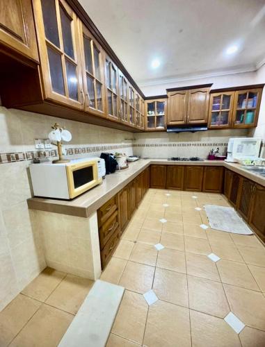 a large kitchen with wooden cabinets and a microwave at Tokma homestay in Kuala Terengganu