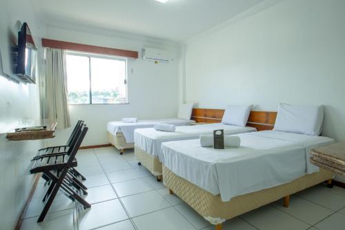 a hotel room with two beds and a window at Rede Andrade Barravento in Ilhéus