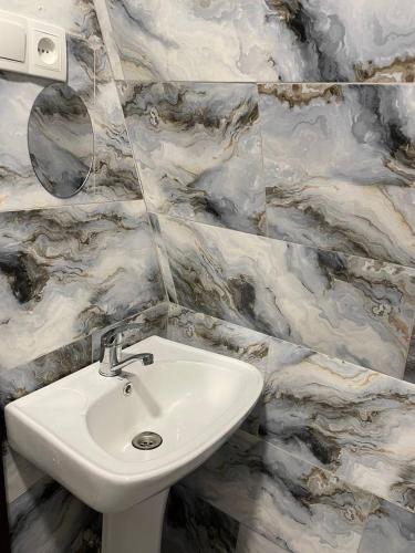 a white sink in a bathroom with marble tiles at Chalet Adjara in Okʼropilauri