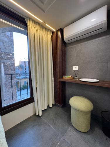 ein Zimmer mit einem Tisch, einem Hocker und einem Fenster in der Unterkunft B in Byblos in Byblos