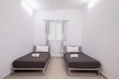 two beds in a room with white walls at Z Express Anoop in Bangalore