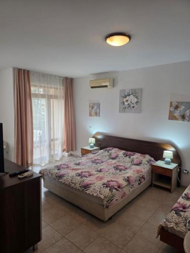 a bedroom with a bed and two tables and a window at Морски Фар in Sveti Vlas