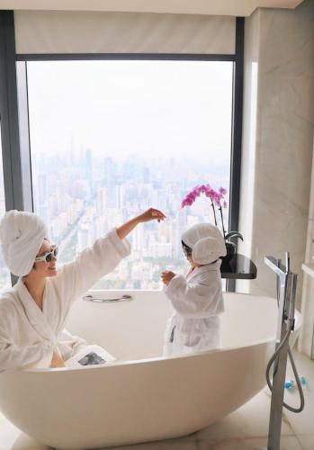 a woman and child in a bath tub in a bathroom at The St. Regis Shenzhen in Shenzhen