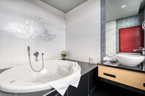 ein Badezimmer mit einer großen Badewanne und einem Waschbecken in der Unterkunft Hotel Verviers Van der Valk in Verviers