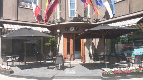 a patio with tables and umbrellas in front of a building at Grand Hotel Viljandi in Viljandi