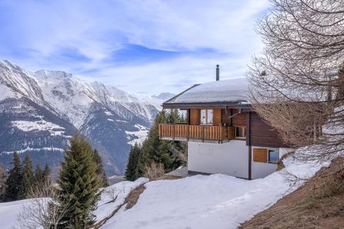 a house on a snowy hill with mountains in the background at Chalet UVA in Bettmeralp