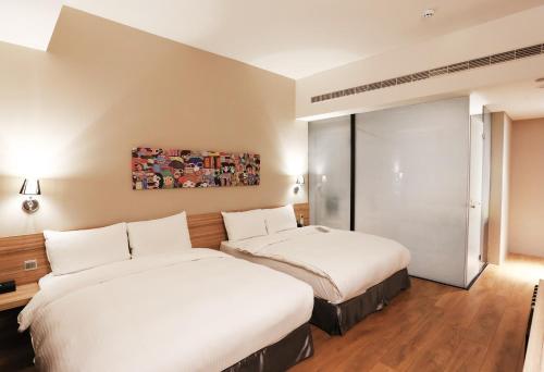 two beds in a hotel room with white sheets at Miller Inn in Taichung