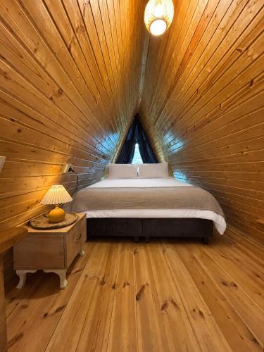 a bedroom with a bed in a wooden room at Chalet Adjara in Okʼropilauri
