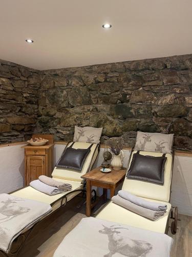 a room with three beds and a stone wall at Haus Edelweiss Alpine Chalet near Samnaun in Spiss