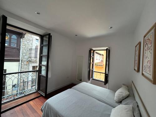 a bedroom with a bed and a large window at Apartamento Manuel Cue en el centro de Llanes in Llanes